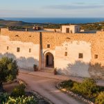 Maison tunisienne traditionnelle avec patio central et murs épais dans un paysage méditerranéen.